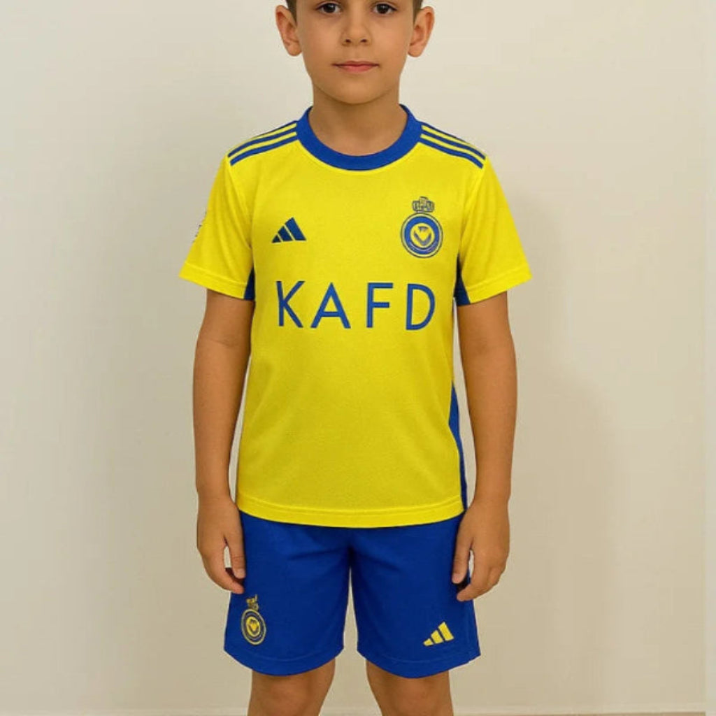 Child wearing a yellow and blue sports outfit with KAFD branding on a plain background