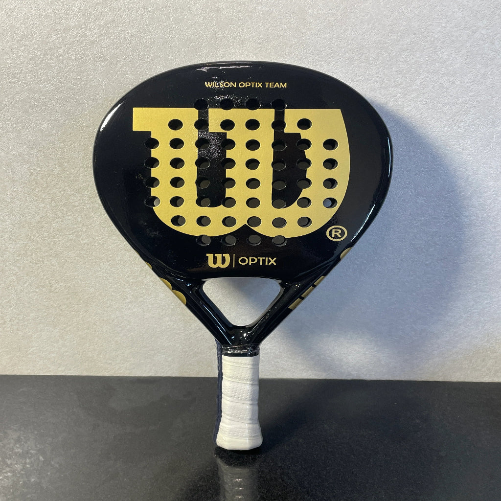 Black and gold Wilson Optix Team racket on a gray background