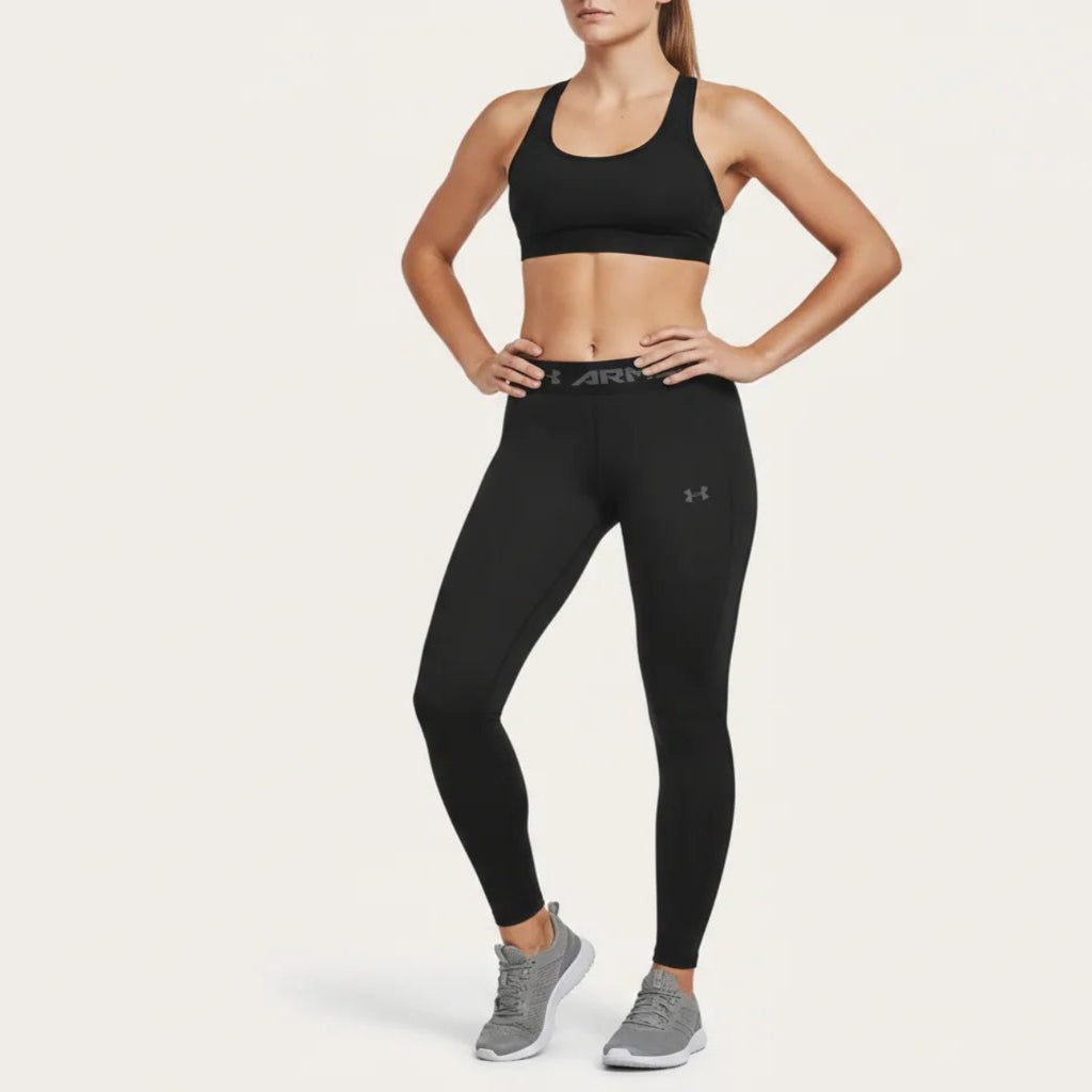 Woman wearing black athletic leggings and sports bra with a visible brand logo on a white background